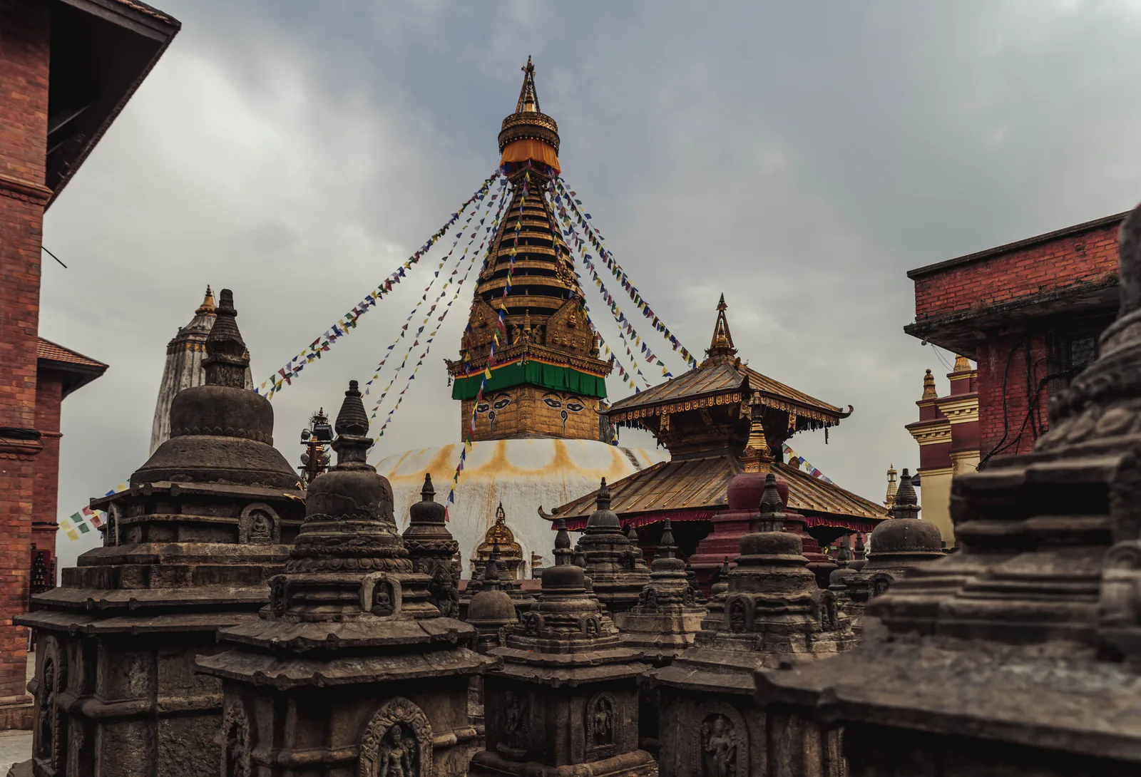 Spectacular view of the Swayambhunath Stupa with vibrant prayer flags under a dramatic sky in Kathmandu, Nepal