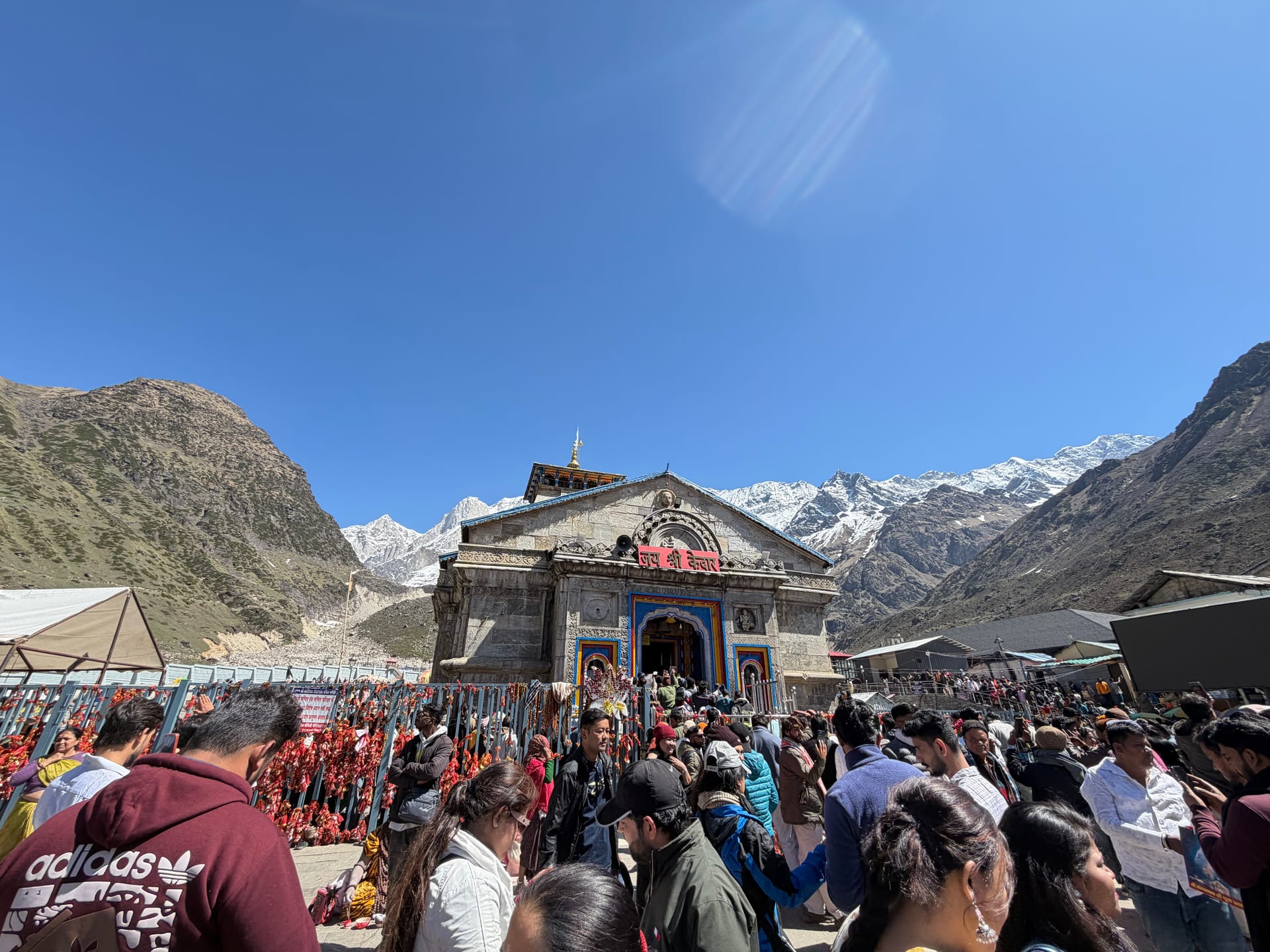 Kedarnath Temple surrounded by Himalayan mountains and pilgrims in Uttarakhand, India.