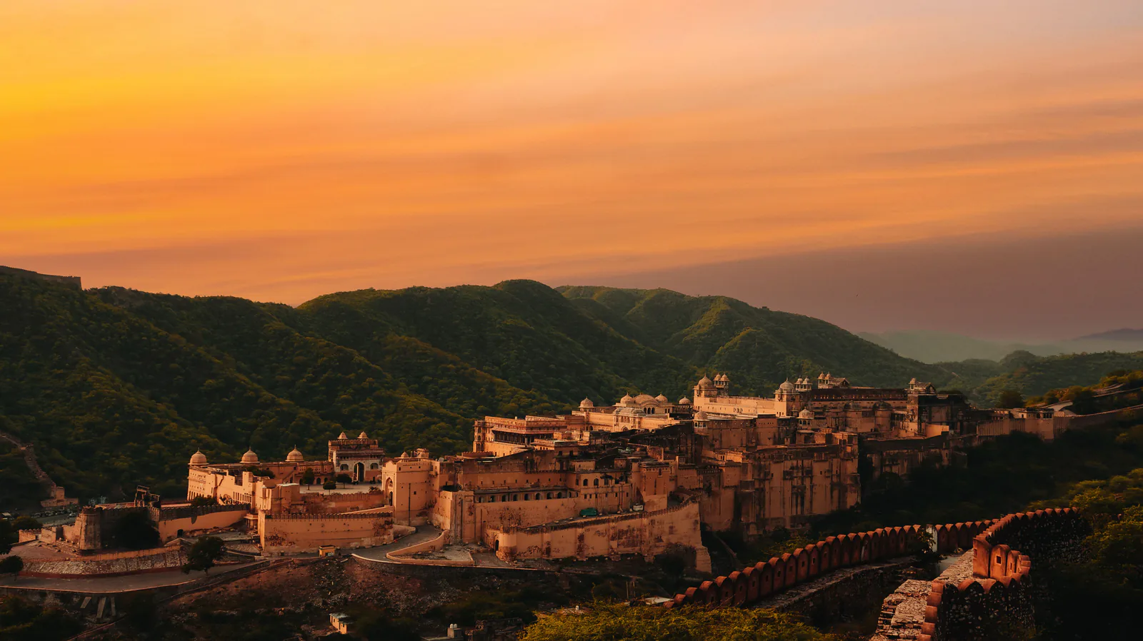 Aerial view of the Amber Fort in Jaipur, Rajasthan, glowing under a vibrant sunset sky