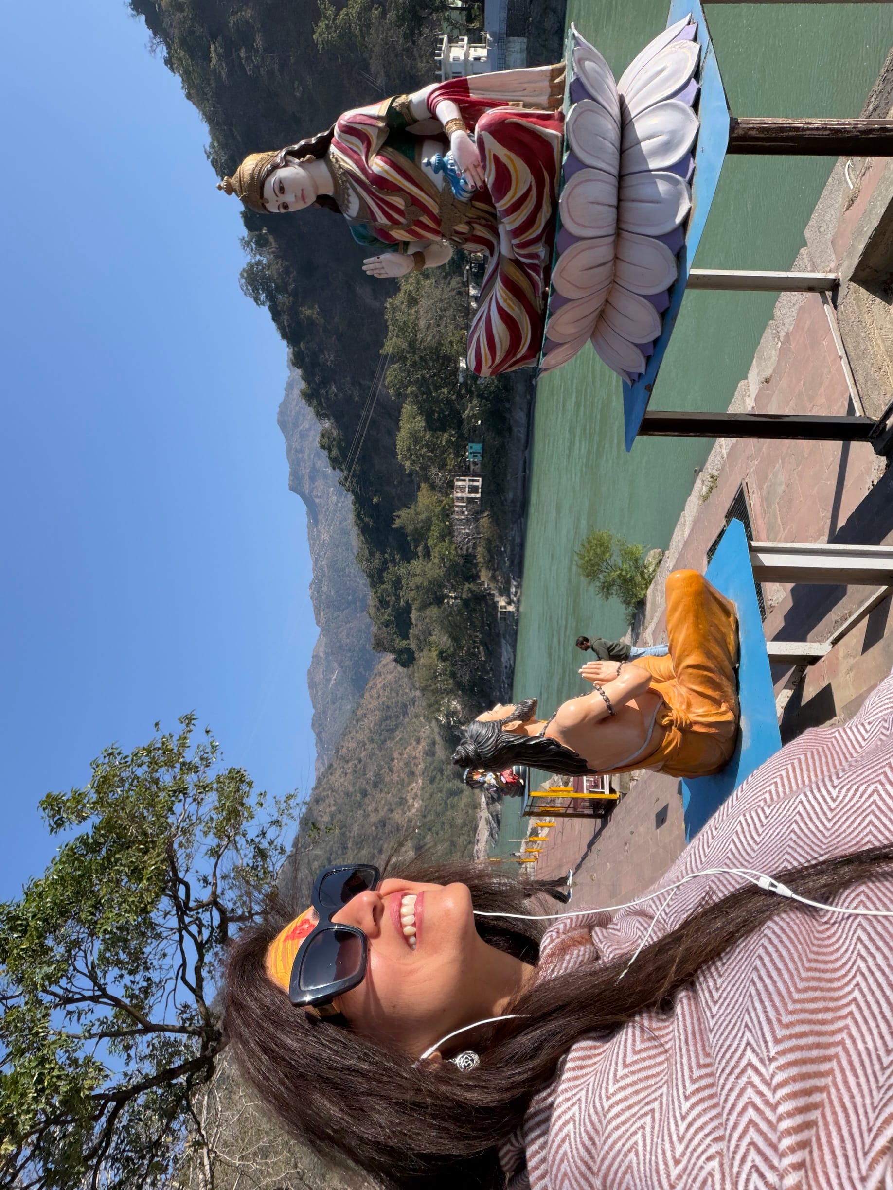 Pamela, Founder of Soul India Journeys, sitting by the Ganges river in Rishikesh, India